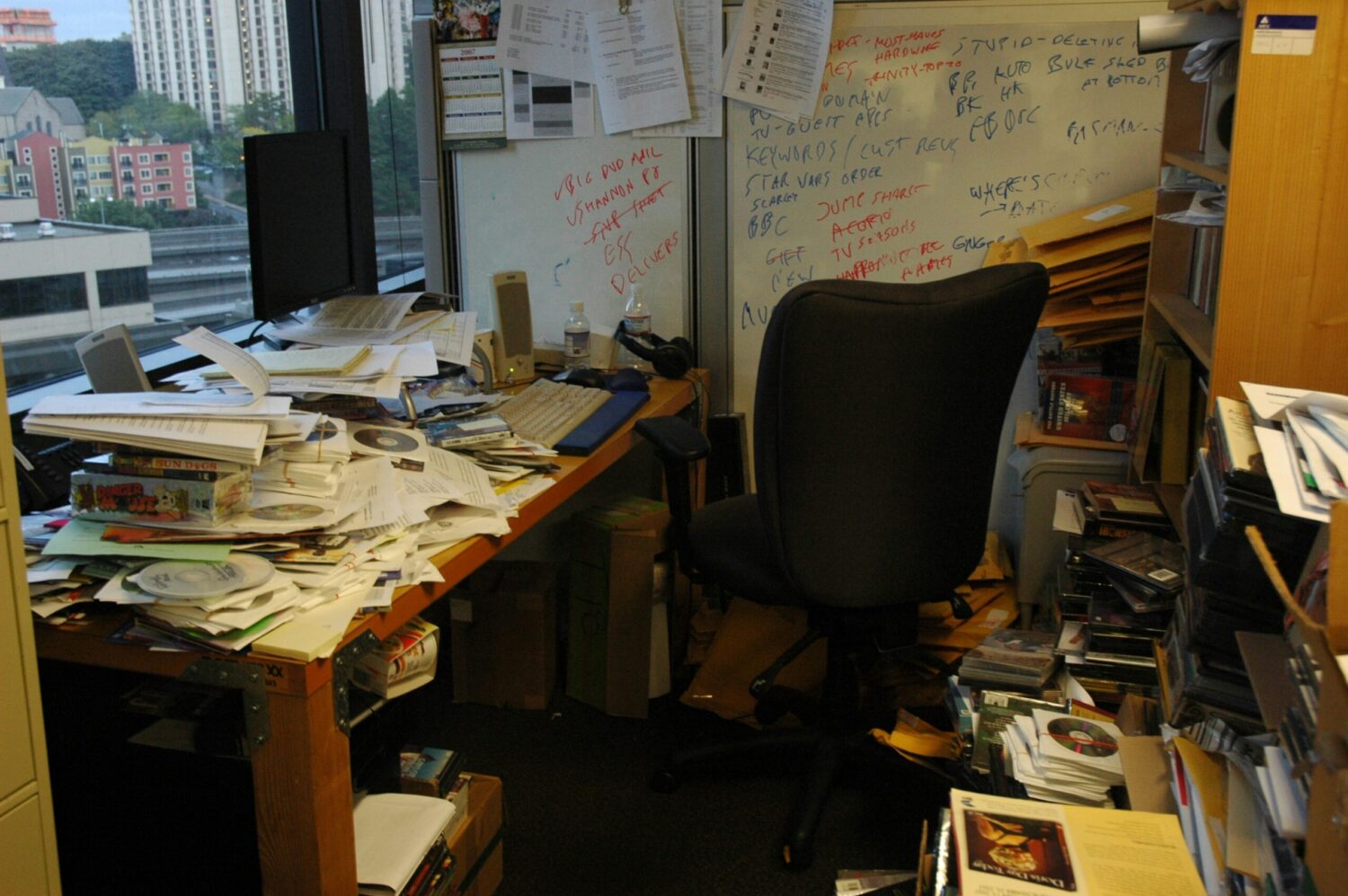 Unordentlicher Schreibtisch im Homeoffice mit Papieren, Büchern und CDs – Beispiel für fehlende Ordnung am Arbeitsplatz.